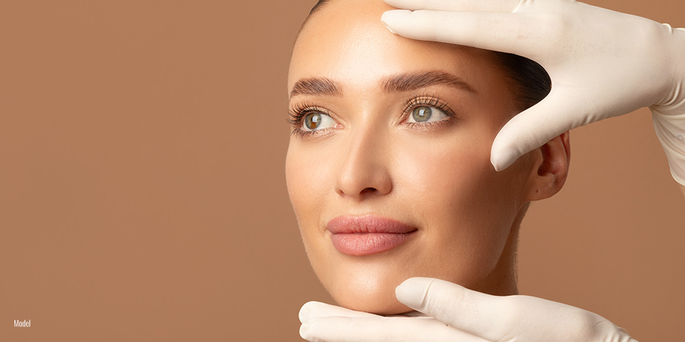 Female close up face with plastic surgeon hands over the face